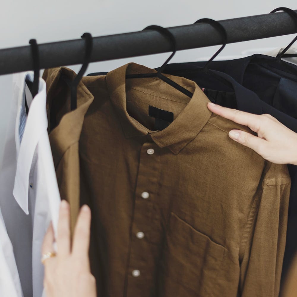 person look at shirts hangign at store